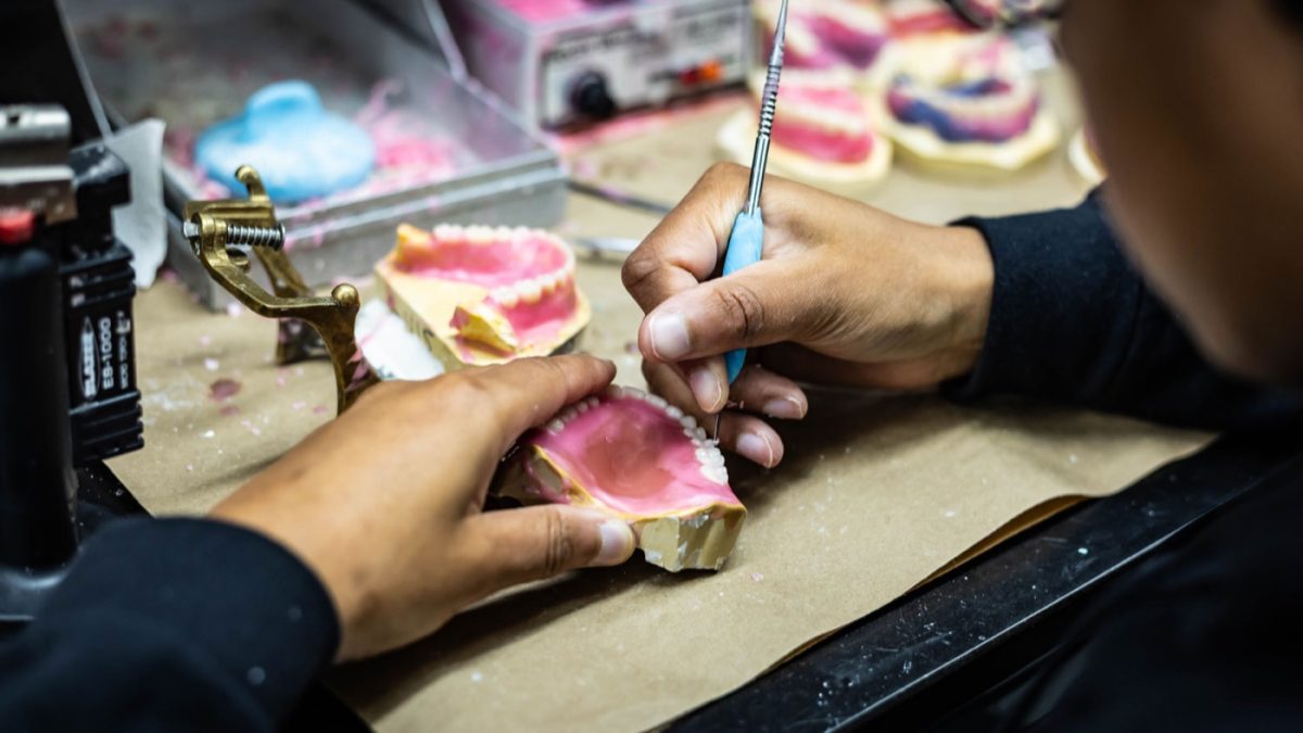 IDA technician working a denture case by hand at the bench