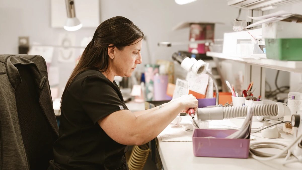 IDA technician working a case with a handpiece at the laboratory bench in Tulsa